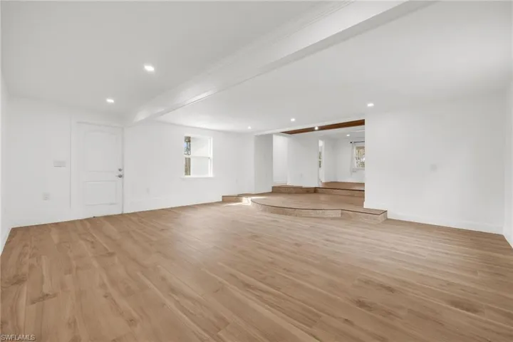 Unfurnished living room featuring beamed ceiling and light hardwood / wood-style floors