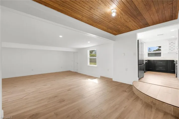 Unfurnished living room with ornamental molding, wood ceiling, and light hardwood / wood-style floors