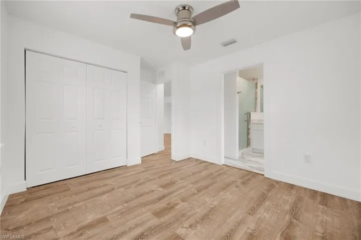 Unfurnished bedroom with ceiling fan, ensuite bath, light hardwood / wood-style flooring, and a closet
