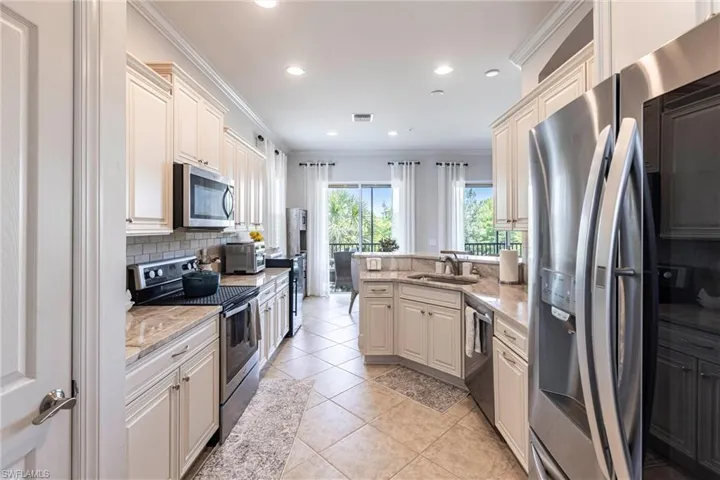 Kitchen with stainless steel appliances, a sink, ornamental molding, tasteful backsplash, and a peninsula