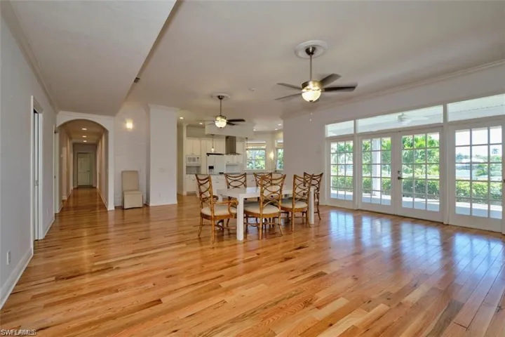 Living room with ceiling fan, ornamental molding, a healthy amount of sunlight, and light wood-type flooring