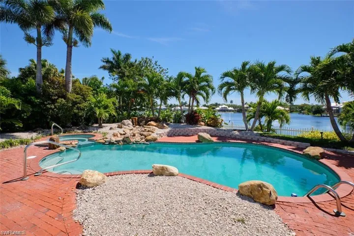 View of swimming pool featuring a water view and an in ground hot tub