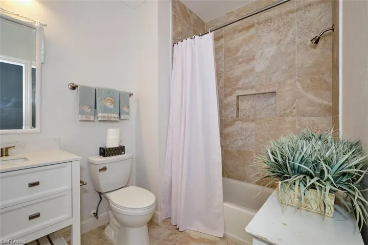 Full bathroom with tile patterned floors, vanity, toilet, and shower / bath combo with shower curtain