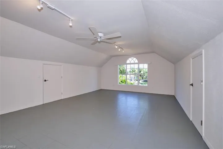 Bonus room over the garage featuring a textured ceiling, vaulted ceiling, and ceiling fan
