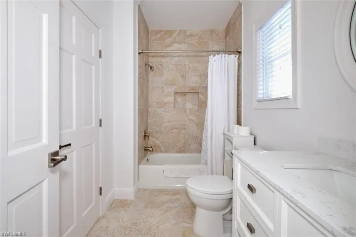 Full bathroom featuring vanity, shower / bathtub combination with curtain, and toilet