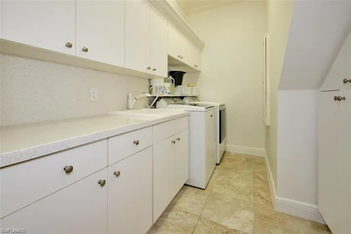 Laundry area featuring washing machine and clothes dryer, sink, and cabinets