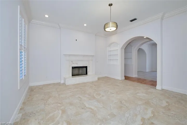 Unfurnished living room with a high end fireplace, built in shelves, and ornamental molding