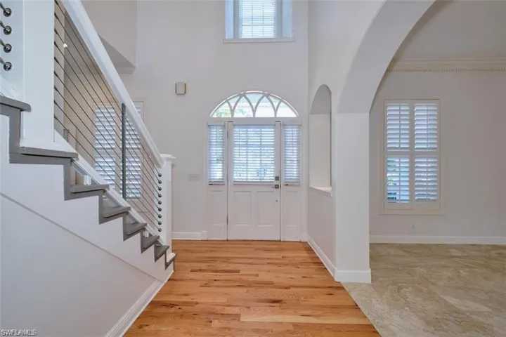 Foyer entrance with a high ceiling, light hardwood / wood-style floors, and crown molding