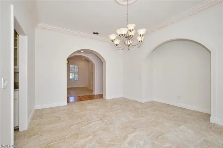 Unfurnished room with a notable chandelier and crown molding
