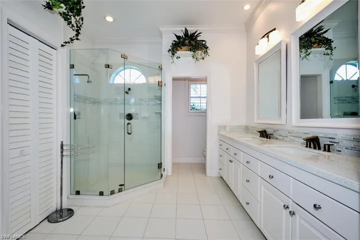 Master bathroom with an enclosed shower, decorative backsplash, toilet, and ornamental molding