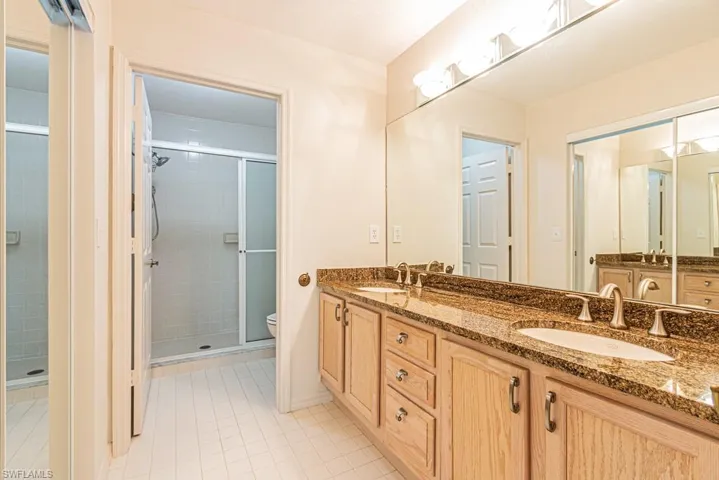 Full bath featuring double vanity, light tile patterned floors, and a stall shower