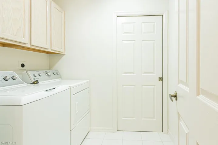 Laundry room featuring light tile patterned flooring, washer and dryer, and cabinet space