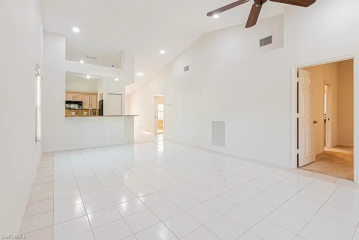 Unfurnished living room featuring high vaulted ceiling, light tile patterned floors, a ceiling fan, and recessed lighting