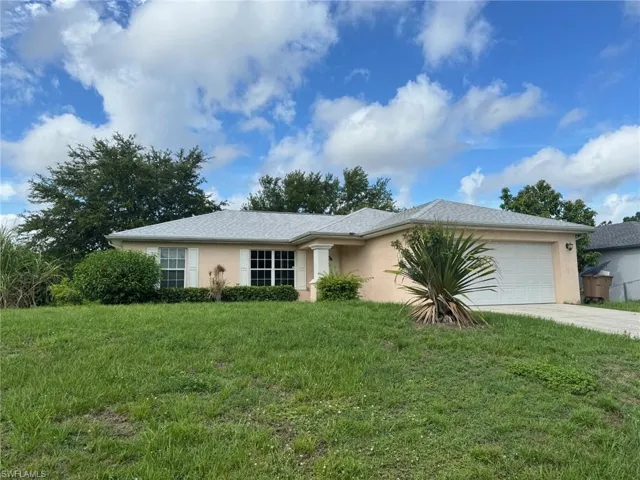 Ranch-style house with a garage, a front lawn, concrete driveway, and stucco siding
