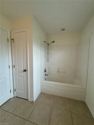 Bathroom featuring baseboards, shower / bathing tub combination, and tile patterned floors