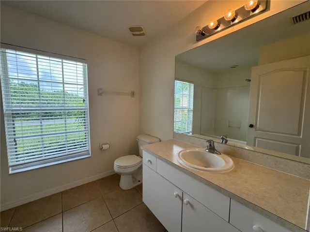 Full bathroom featuring visible vents, toilet, tile patterned floors, walk in shower, and vanity