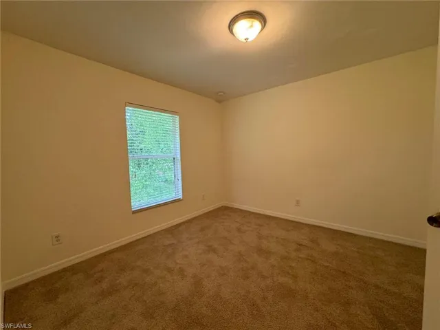 Empty room featuring baseboards and dark carpet