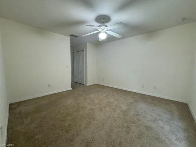 Spare room with baseboards, carpet, visible vents, and a ceiling fan
