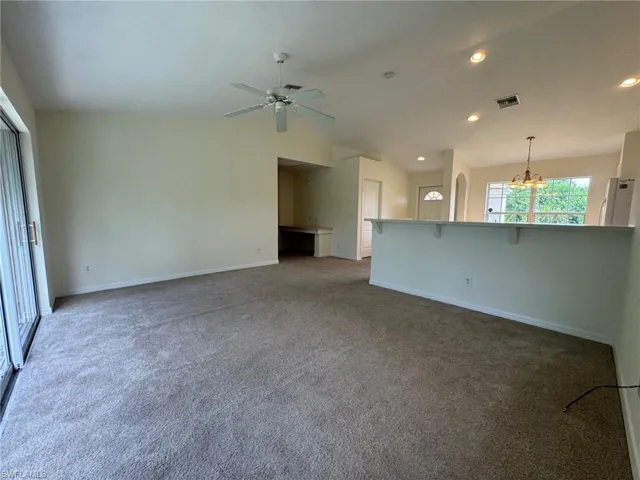 Unfurnished living room featuring carpet floors, recessed lighting, baseboards, and ceiling fan with notable chandelier