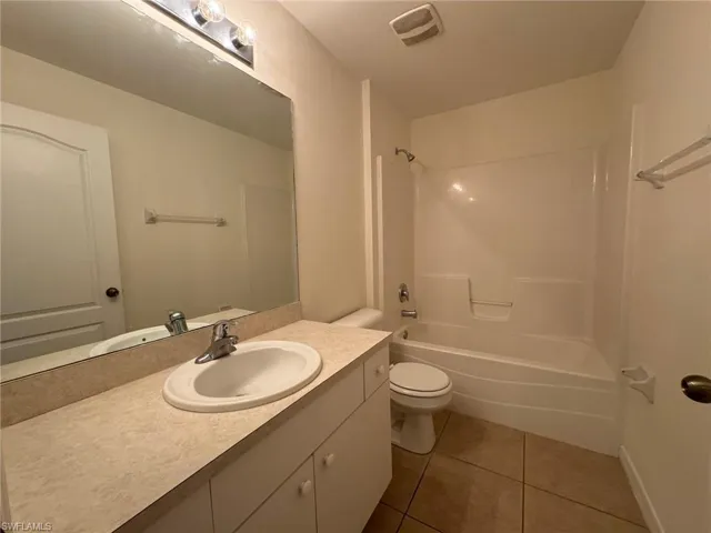 Bathroom featuring shower / washtub combination, visible vents, toilet, vanity, and tile patterned flooring