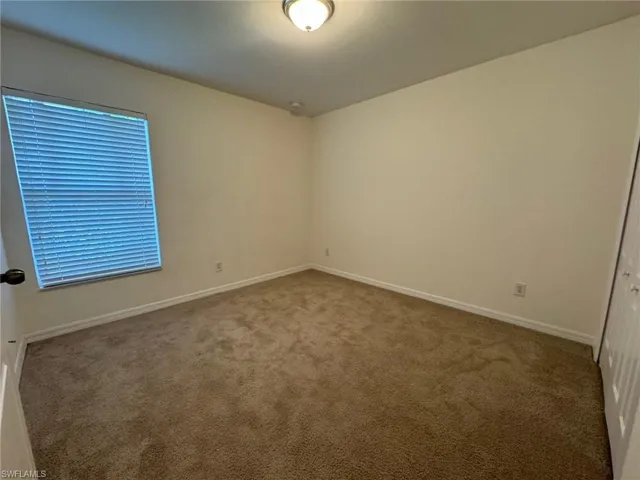 Carpeted empty room featuring baseboards