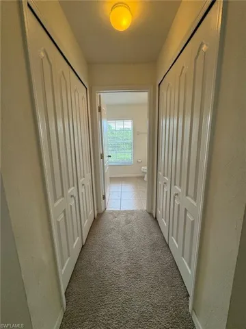 Hall featuring light carpet and light tile patterned floors