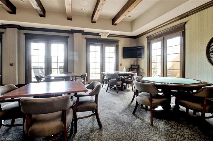 Carpeted dining room with french doors, plenty of natural light, beamed ceiling, and wallpapered walls