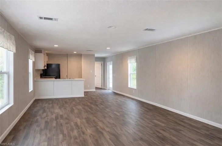 Unfurnished living room with dark wood-style floors, a textured ceiling, and recessed lighting