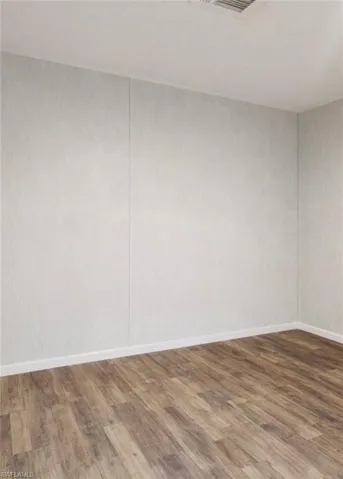 Unfurnished room with dark wood-type flooring and baseboards