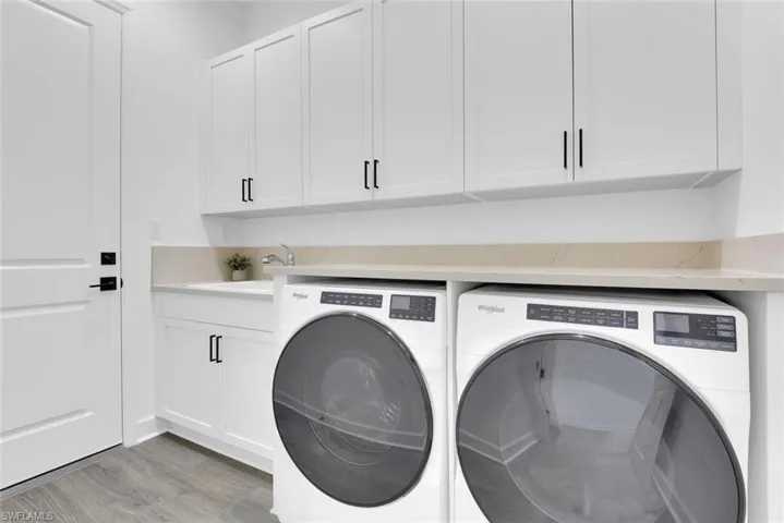 Washroom with cabinet space, light wood finished floors, separate washer and dryer, and a sink