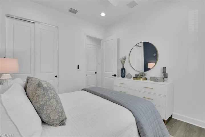 Bedroom featuring wood finished floors, baseboards, a closet, and visible vents