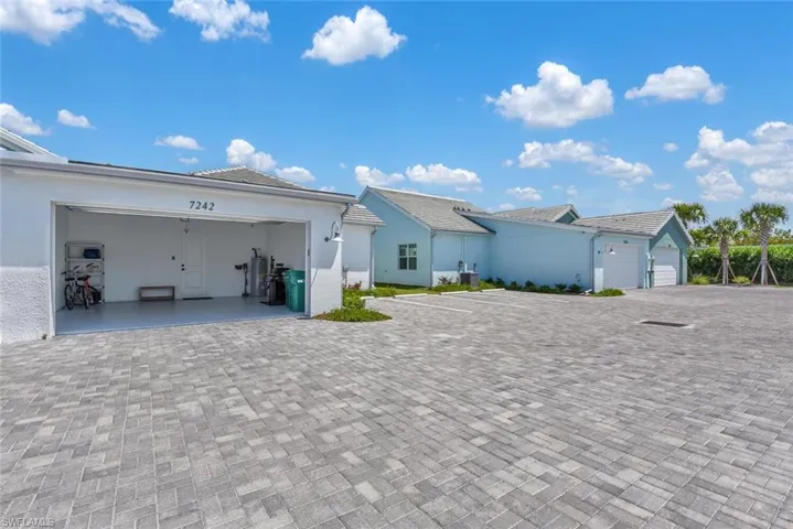 Rear view of property featuring a garage, stucco siding, a tiled roof, and decorative driveway