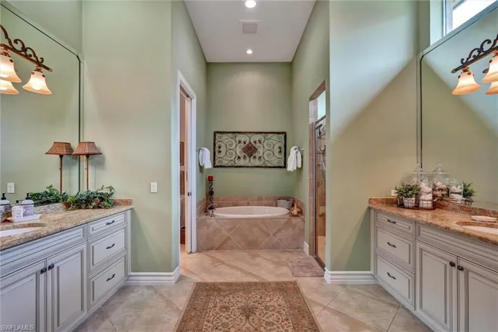 Spacious bathroom featuring dual vanities with light cabinetry and granite countertops