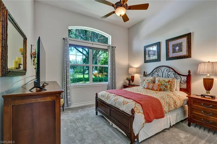 Vaulted ceiling with a ceiling fan, arched transom window, and a large multi-pane window