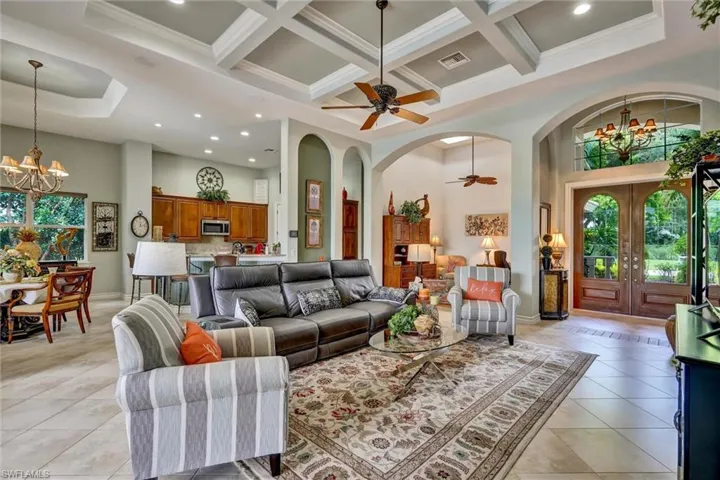 Open-concept living area featuring a coffered ceiling, ceiling fan, and large format tile flooring