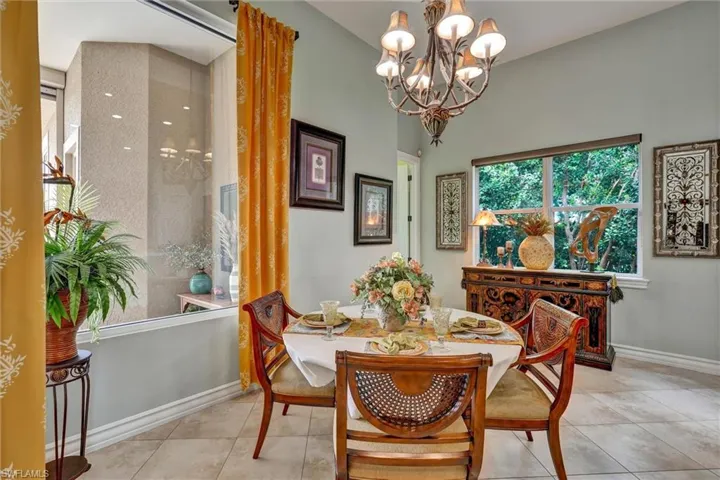 Dining area featuring a vaulted ceiling, tile flooring, and a decorative chandelier