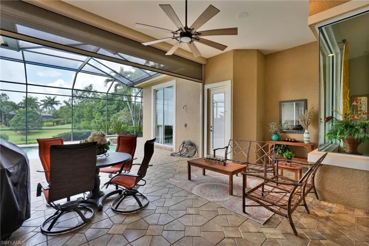 Expansive screened lanai featuring geometric patio pavers, a large ceiling fan, and direct access to the exterior landscape