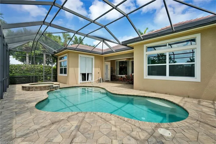 Screened lanai featuring a freeform swimming pool and integrated spa