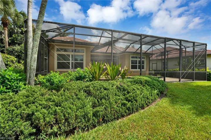 Screened patio enclosure with a tiled roof residence, surrounded by lush landscaping and mature palm trees