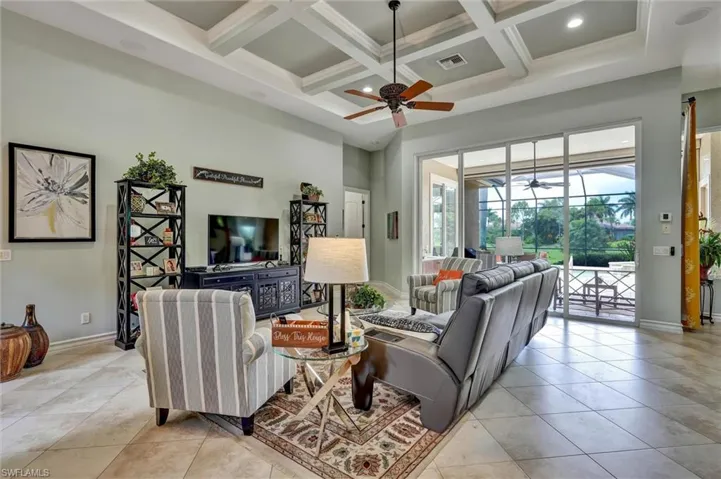 Living area featuring large format tile flooring, a coffered ceiling with recessed lighting, and a ceiling fan