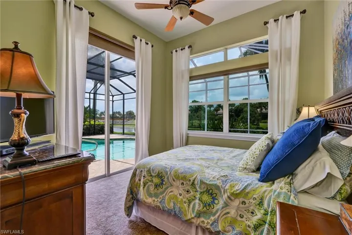 Bedroom featuring sliding glass doors to a screened lanai with a pool, water, and tropical foliage