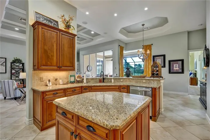 Kitchen featuring warm-toned wood cabinetry, granite countertops, an island with additional storage, stainless steel appliances, and tile flooring