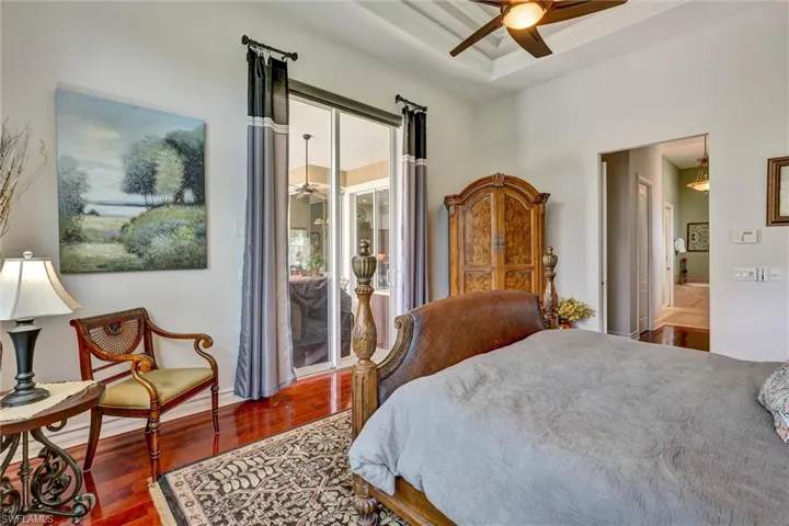 Tray ceiling with a ceiling fan, recessed lighting, and wood-finish flooring
