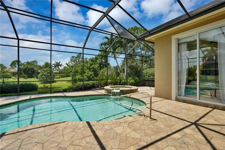 Screened lanai featuring a swimming pool, integrated spa, and expansive paver patio
