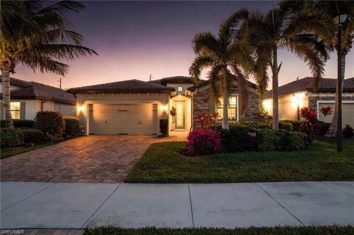 Elegant twilight exterior featuring tropical landscaping, paver driveway, and welcoming curb appeal at 9216 Woodhurst.