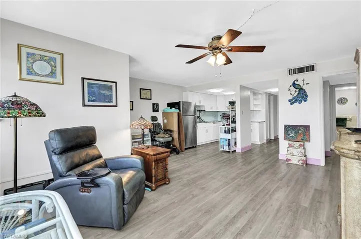 Living room featuring baseboard heating, ceiling fan, and light wood-type flooring