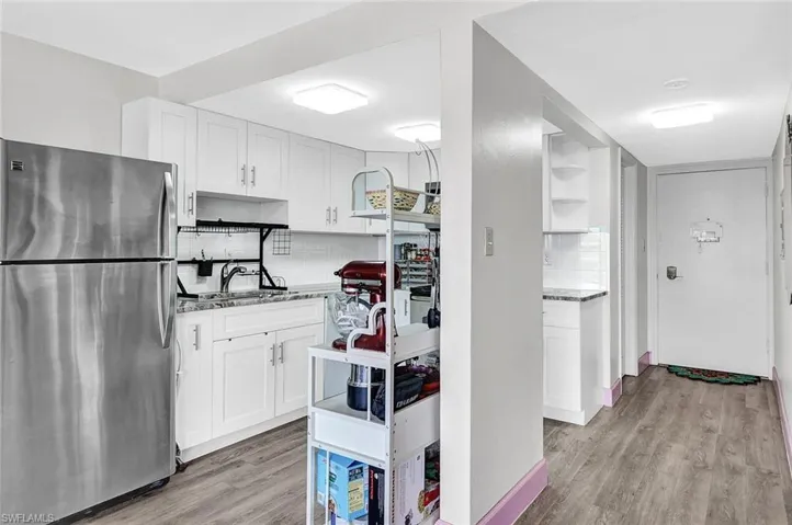 Kitchen featuring white cabinetry, backsplash, stainless steel fridge, and light wood-type flooring