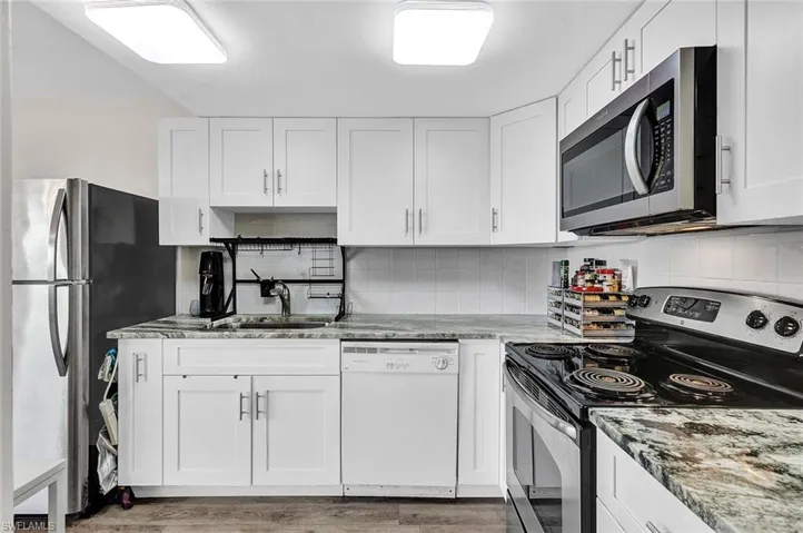 Kitchen with white cabinetry, tasteful backsplash, stainless steel appliances, and hardwood / wood-style floors