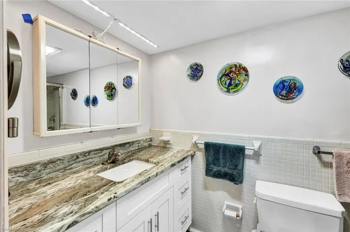 Bathroom with vanity, toilet, tasteful backsplash, and tile walls