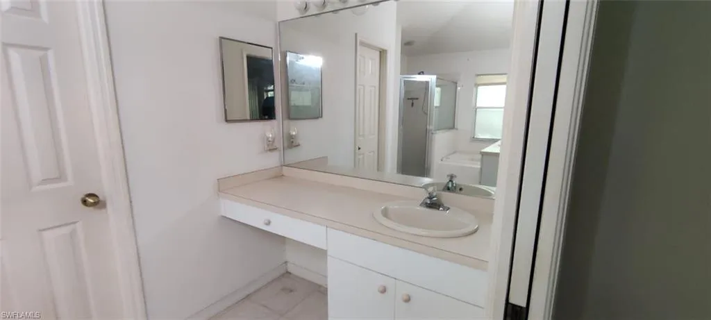 Bathroom with tile patterned floors, an enclosed shower, and vanity